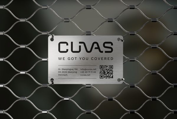 Brushed steel tag with the CUVAS logo, payoff and contact details, mounted on the stainless-steel net